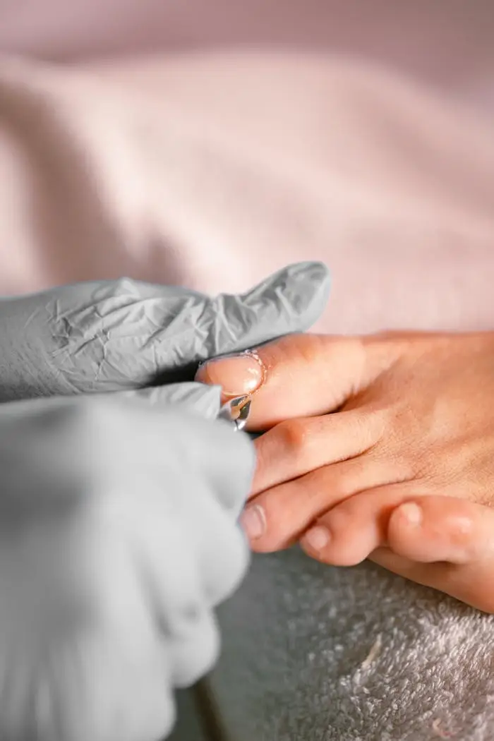 about-img Close-up of a pedicure session with protective gloves and focus on the toenail treatment.